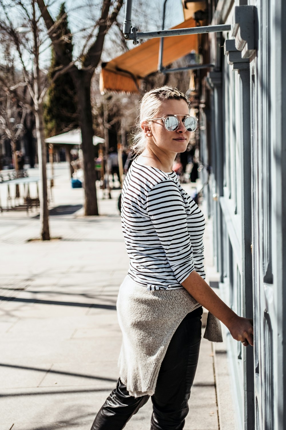 a woman leaning against a building on a sidewalk