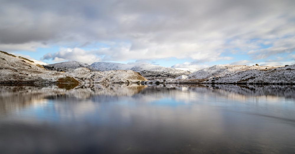 body of water near mountain covered by snow