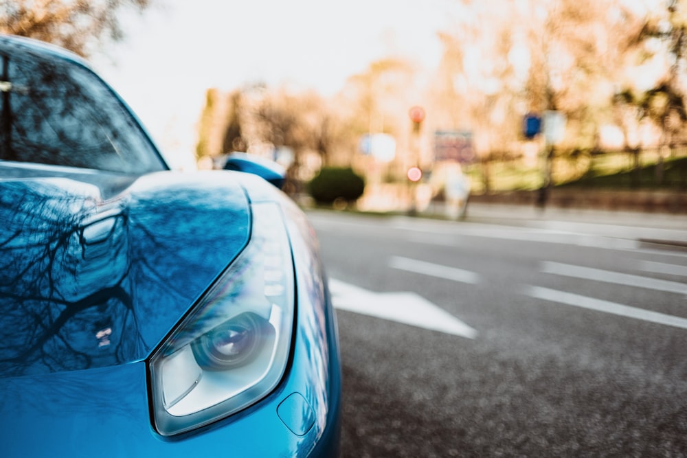 blue car parked beside the road near trees