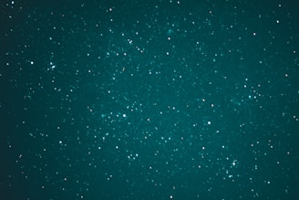 A vast expanse of the night sky is speckled with countless stars, creating a breathtaking celestial scene. The stars vary in brightness and are scattered across a deep, teal background, evoking a sense of wonder and the infinite nature of the universe.
