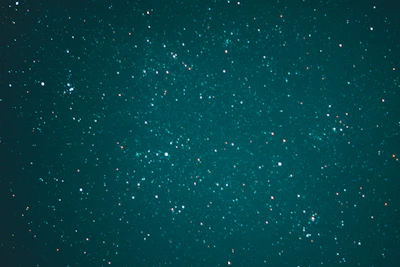 A vast expanse of the night sky is speckled with countless stars, creating a breathtaking celestial scene. The stars vary in brightness and are scattered across a deep, teal background, evoking a sense of wonder and the infinite nature of the universe.