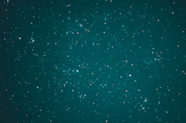 A vast expanse of the night sky is speckled with countless stars, creating a breathtaking celestial scene. The stars vary in brightness and are scattered across a deep, teal background, evoking a sense of wonder and the infinite nature of the universe.
