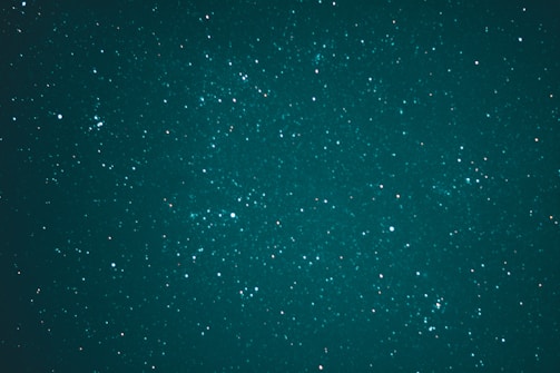 A vast expanse of the night sky is speckled with countless stars, creating a breathtaking celestial scene. The stars vary in brightness and are scattered across a deep, teal background, evoking a sense of wonder and the infinite nature of the universe.