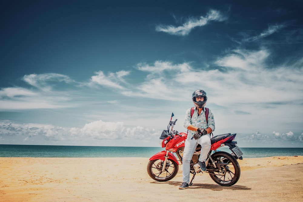 man sitting on red standard motorcycle