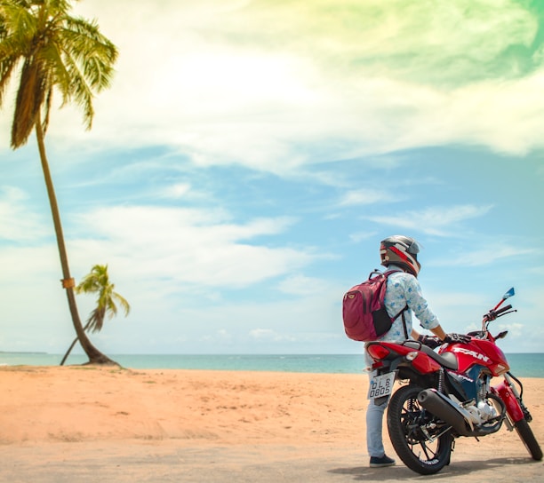 man standing beside red sports bike during daytime