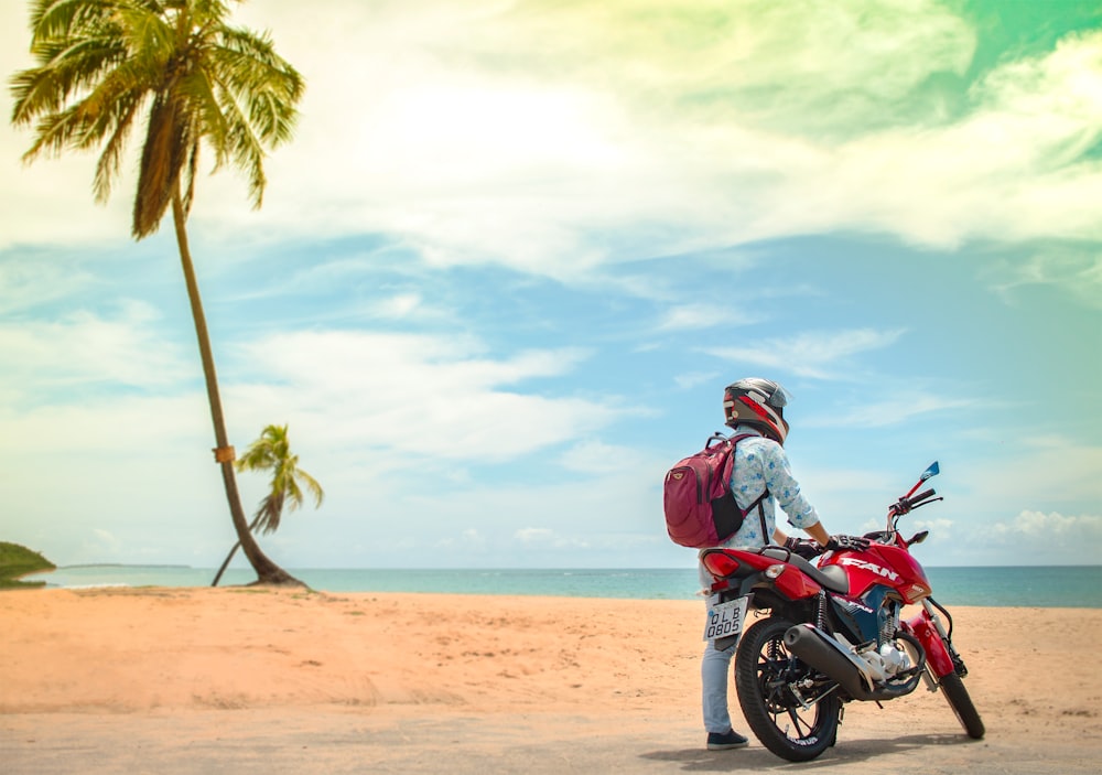 man standing beside red sports bike during daytime