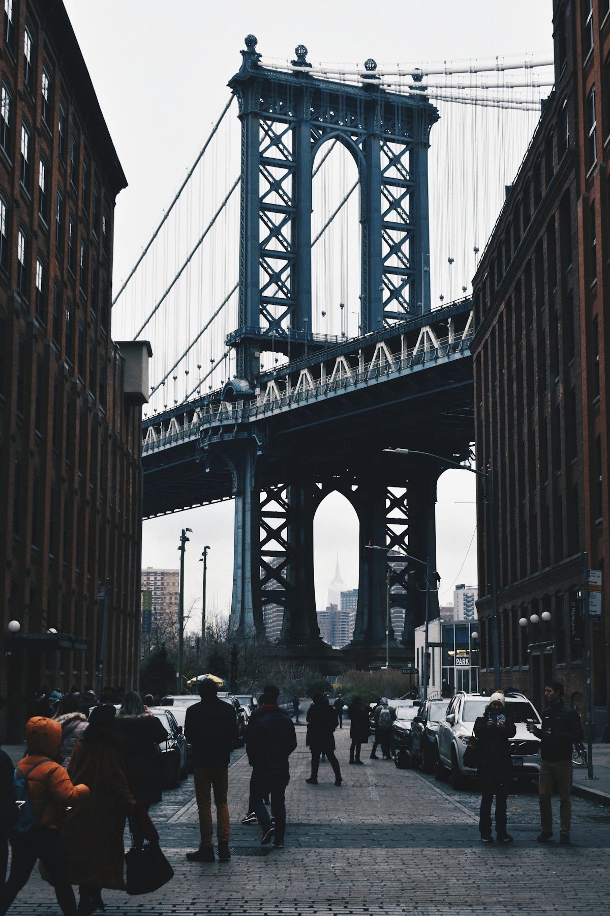 People walking along a cobbled street beneath the Manhattan Bridge in DUMBO