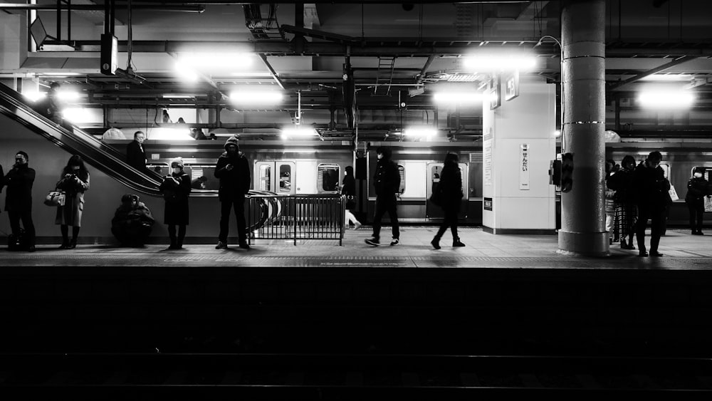 a black and white photo of people standing on a platform