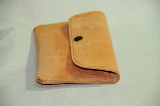 Close-up of a rich brown leather wallet resting on a wooden table with soft natural light.