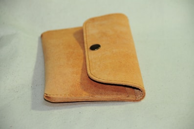 Minimalist tan leather wallet resting on a marble surface with natural light