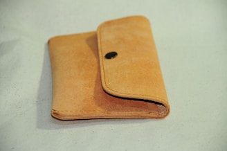Minimalist tan leather wallet resting on a marble surface with natural light