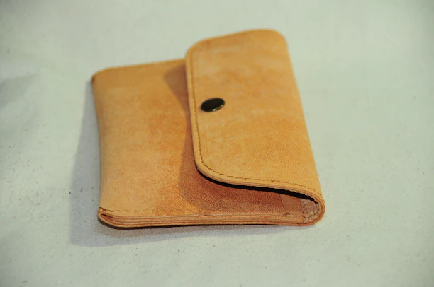 Close-up of a rich brown leather wallet resting on a wooden table with soft natural light.