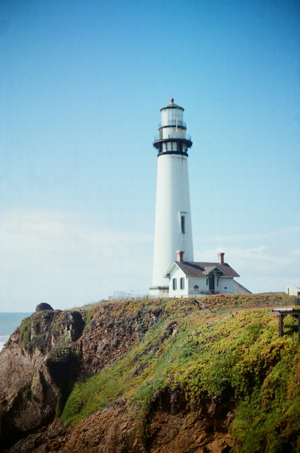 white lighthouse beside house under blue sky