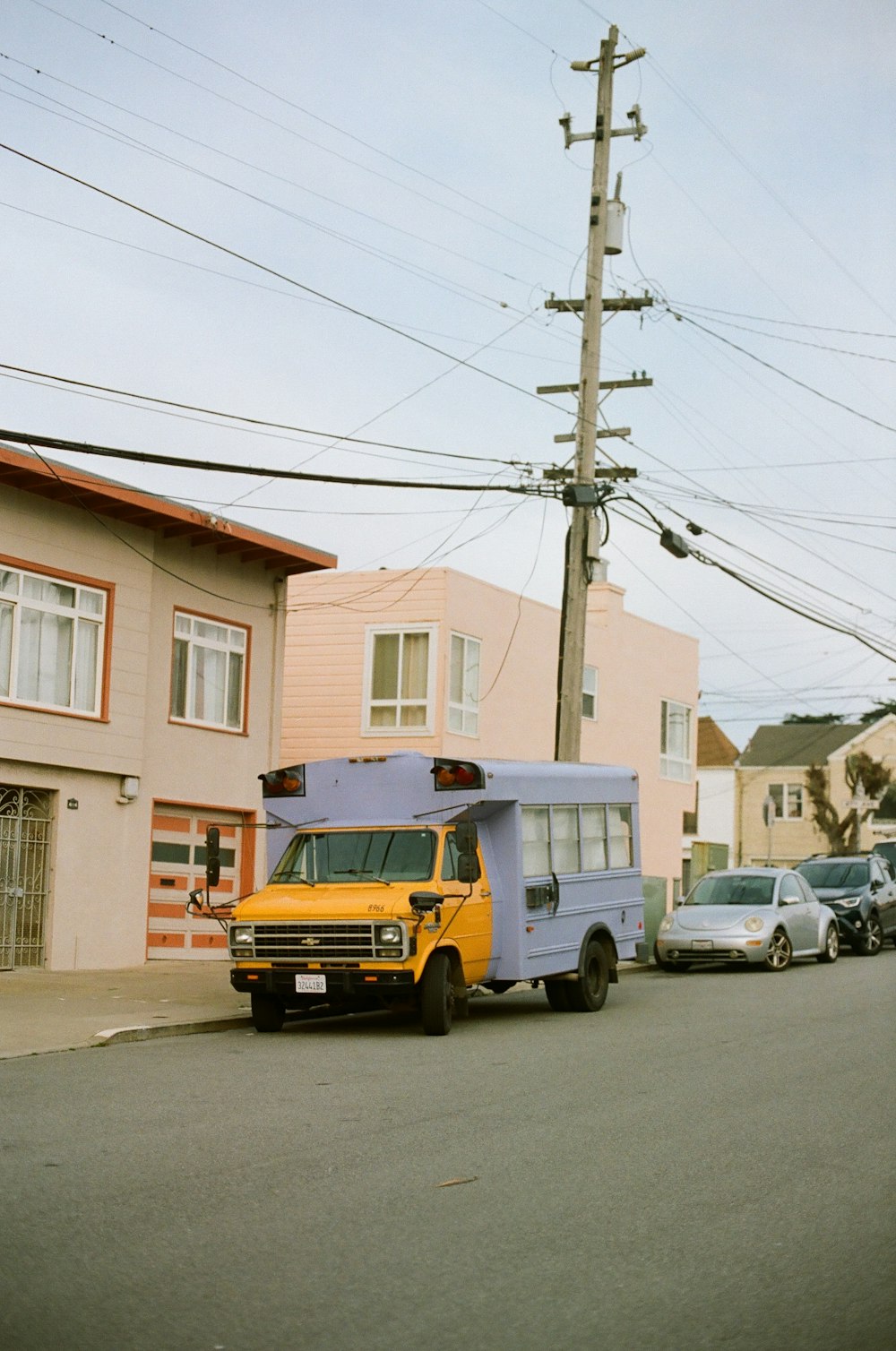 white and yellow vehicle parked near house