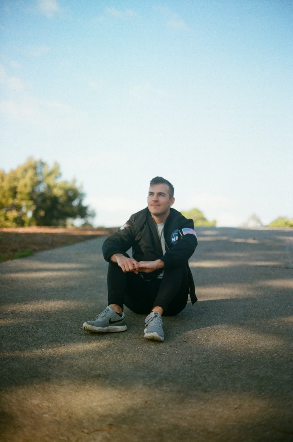 man sitting on road wearing black pants