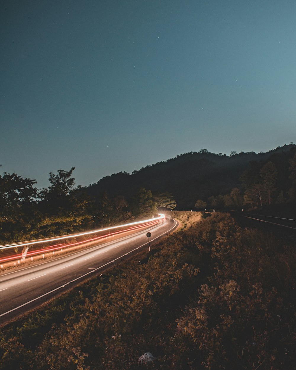 Zeitrafferfotografie eines Autos, das in der Dämmerung auf der Straße läuft