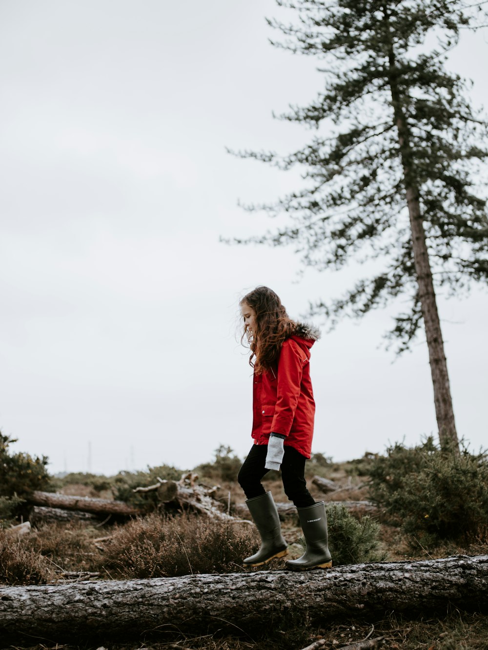 girl in parka walking on tree trunk