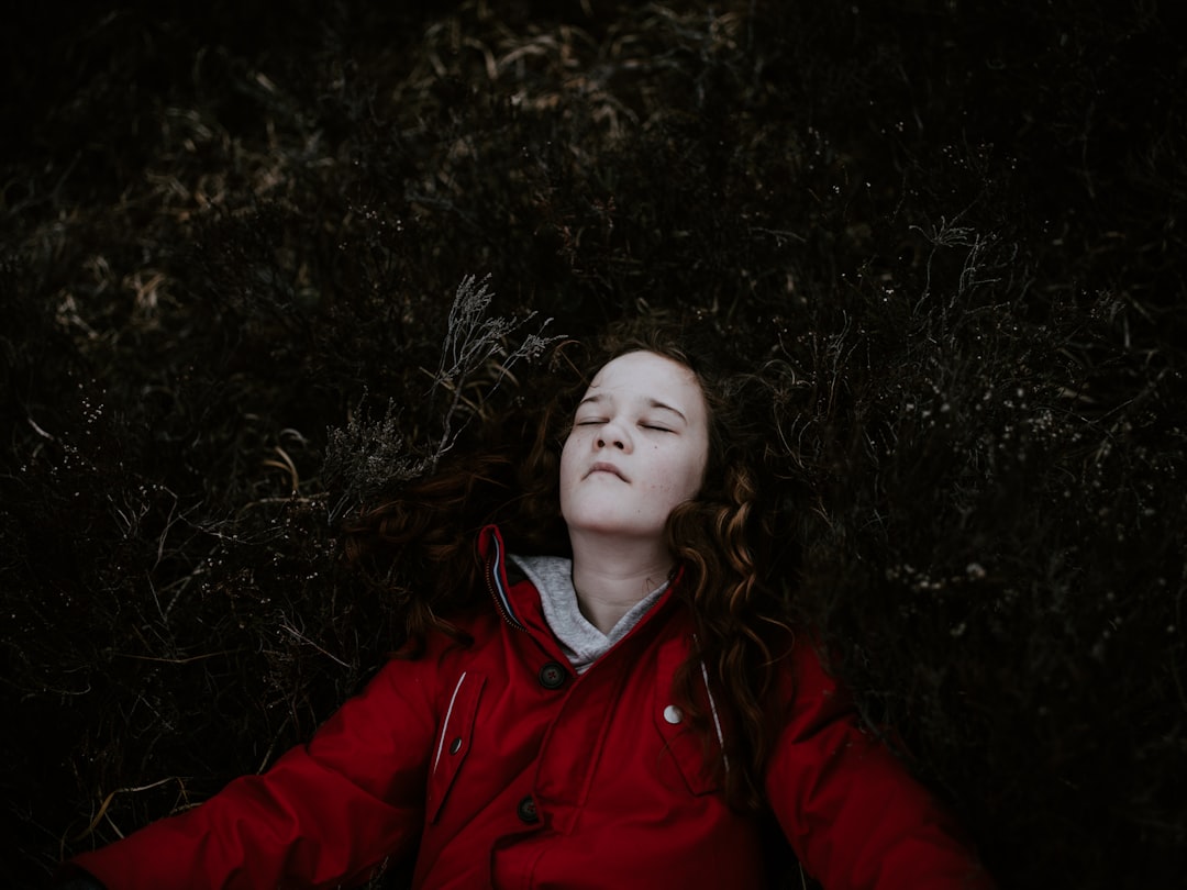 girl lying on ground wearing red jacket