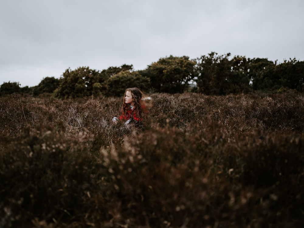 selective focus photography of girl sitting surrounded by plants