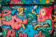 Colorful street art mural bursting with expressive human faces in movement.