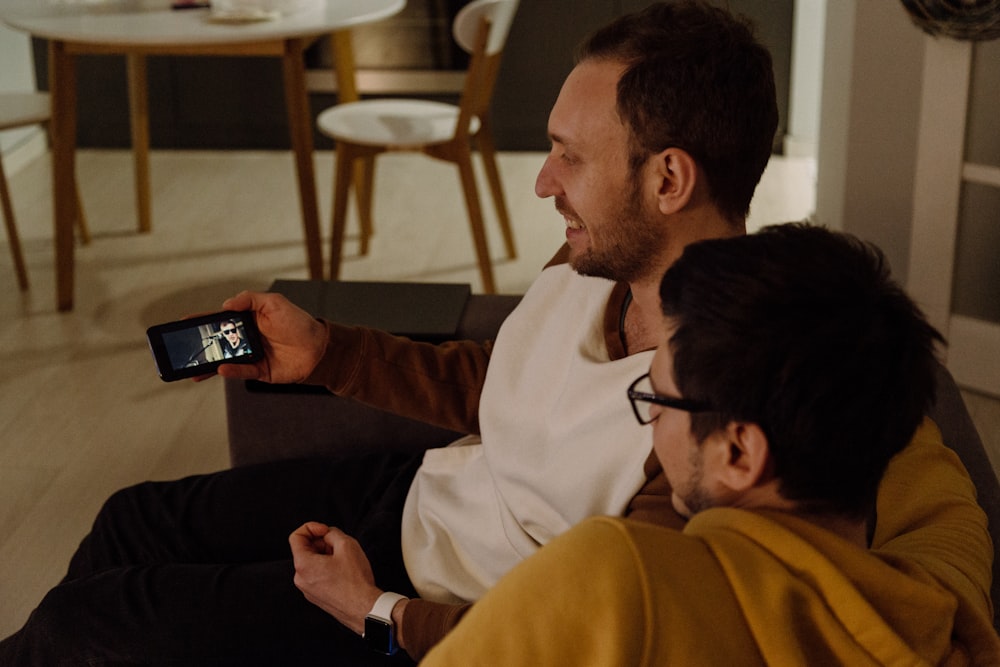 deux hommes assis regardant à partir d’un smartphone