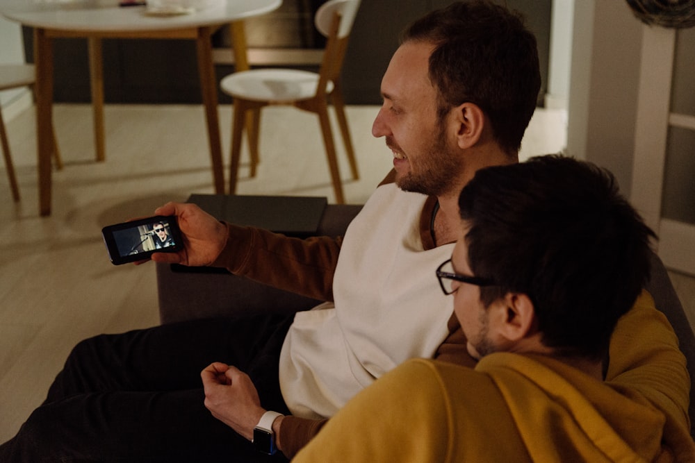 two sitting men watching from smartphone