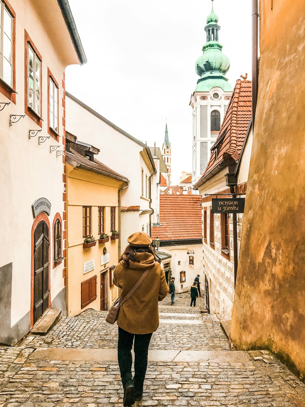 woman walking between brown concrete building