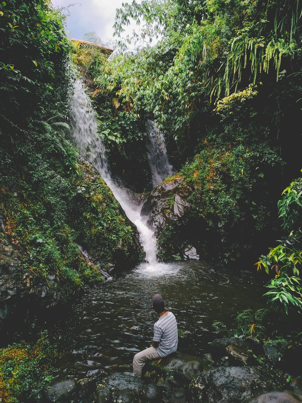 man sitting beside waterfalls