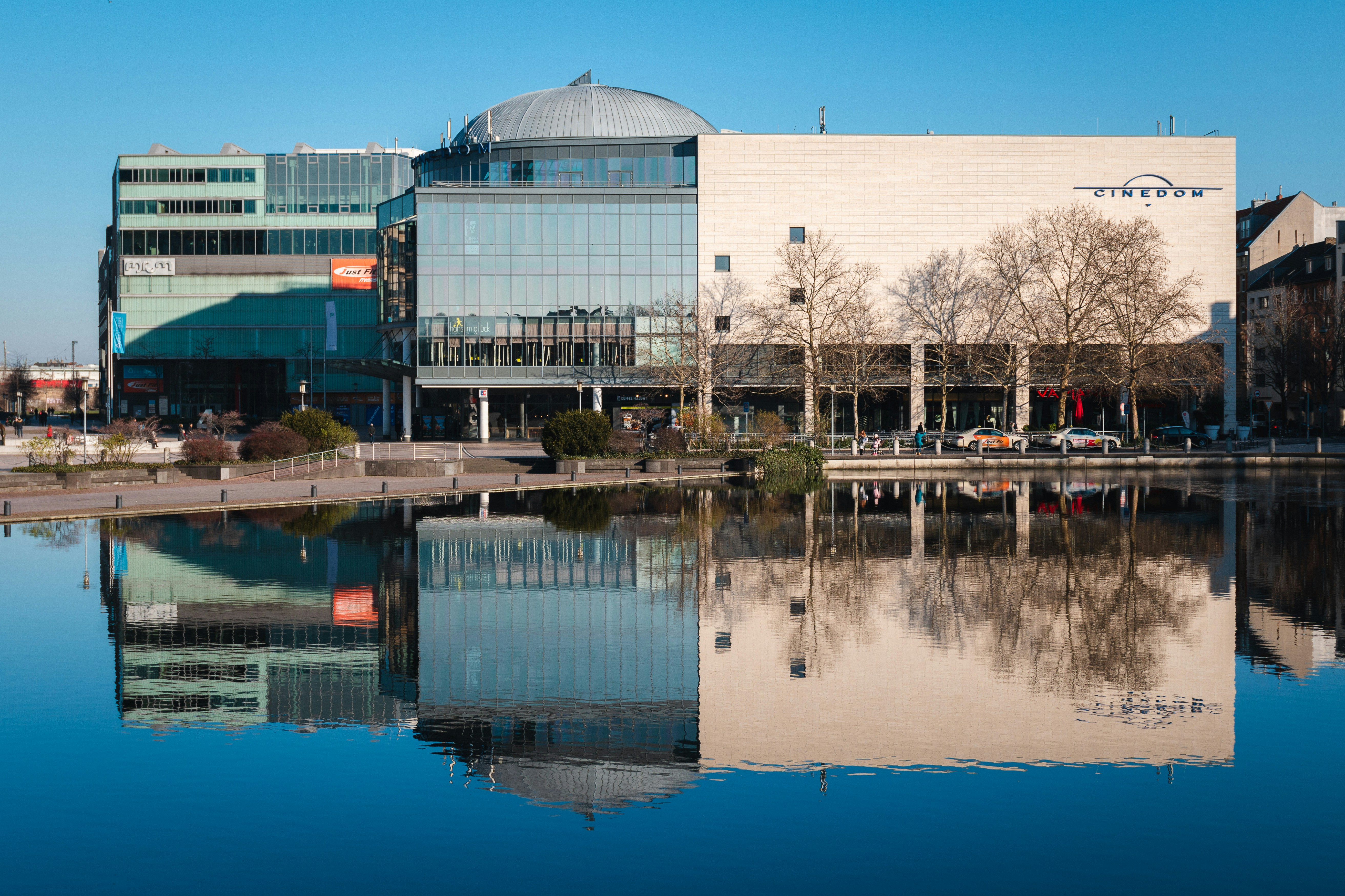 white and gray building showing reflection on body of water