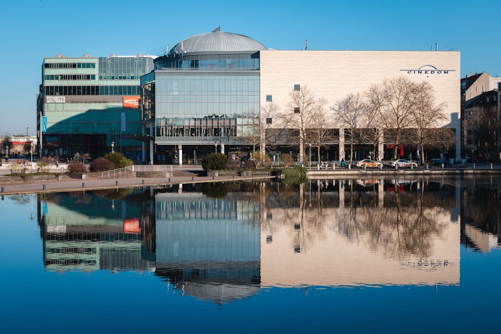 white and gray building showing reflection on body of water