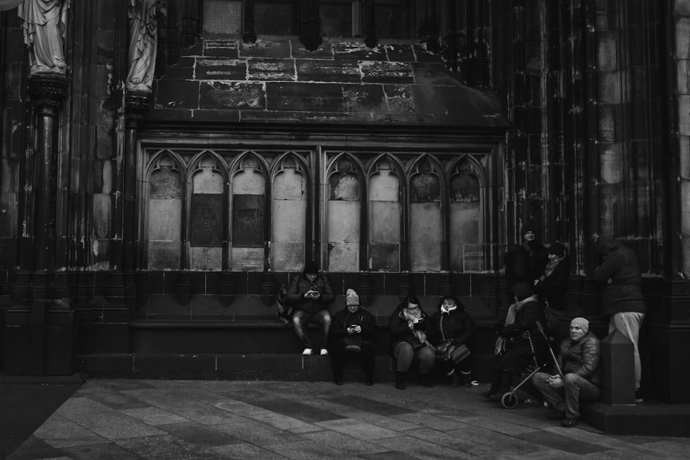 grayscale photography group of person sitting on bench