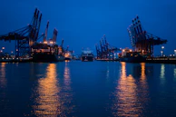 A panoramic view of a bustling maritime port at dusk with silver accents reflecting on the water.