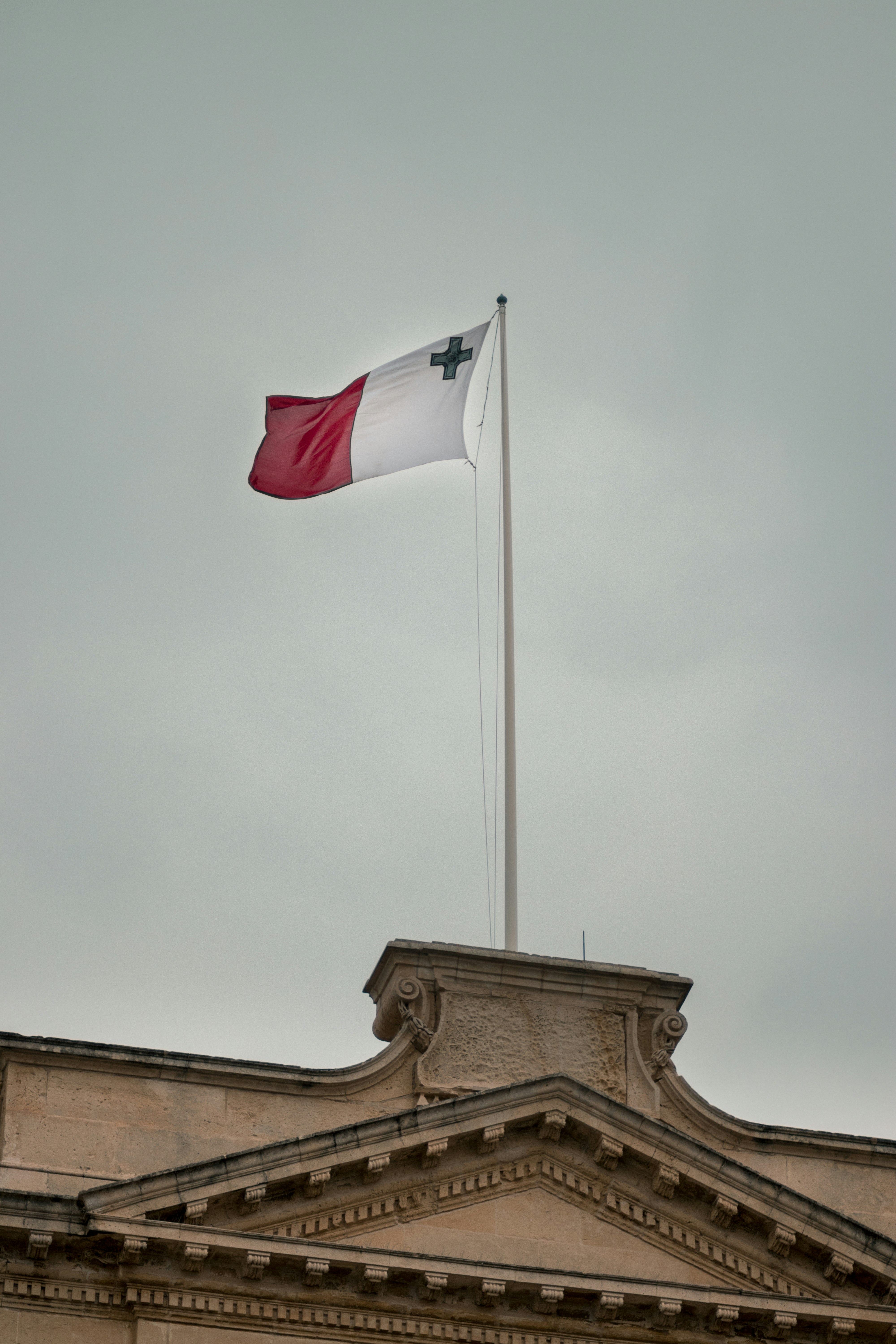 Bandera blanca y roja bajo nubes grises