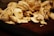 A pile of freshly sliced mushrooms sits on a dark wooden surface. The mushrooms are pale with varying shades of white and light brown, showcasing their fresh texture and natural patterns.