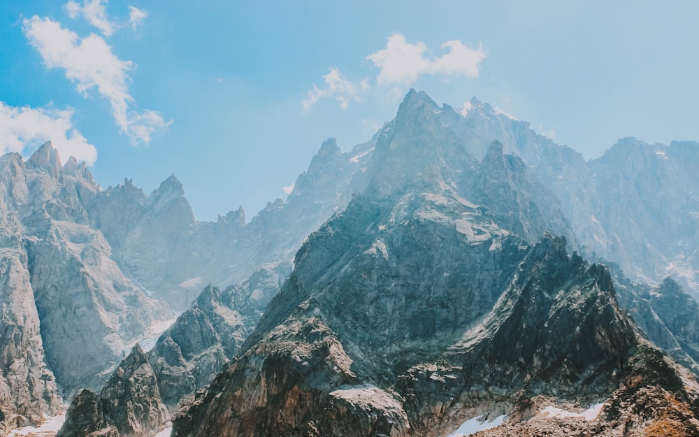 snow covered rocky mountain under white and blue cloudy sky