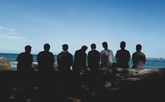 eight man sitting on mountain cliff under blue sky