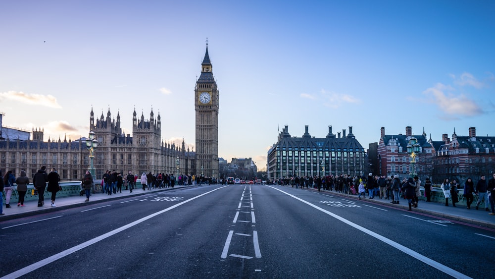 people with coats walking along the sidewalks on empty street near Big Ben