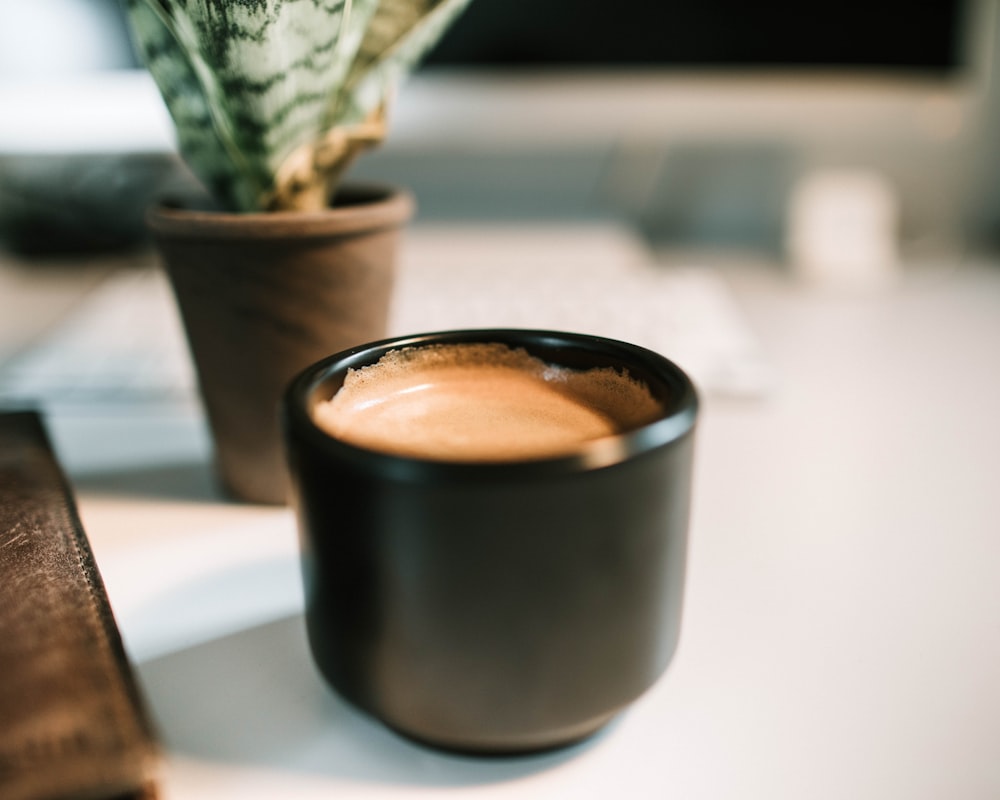 Caneca de cerâmica preta cheia de café na fotografia de foco seletivo
