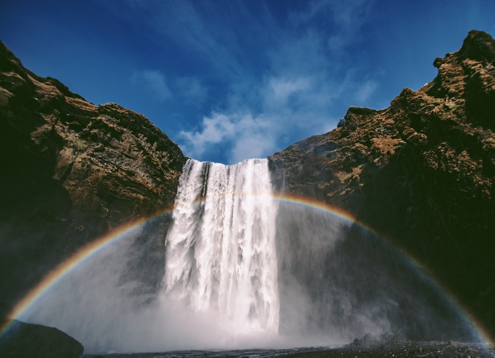 Tiefwinkelfotografie von Wasserfällen mit Regenbogen bei Tag