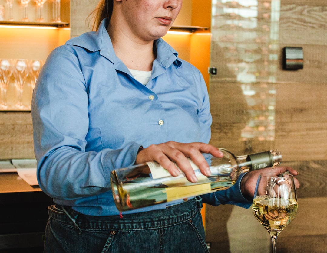 woman holding wine bottle and putting wine on wine glass