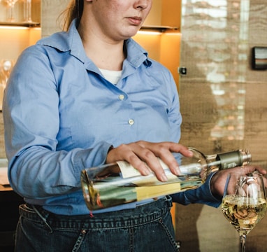 woman holding wine bottle and putting wine on wine glass