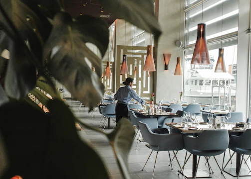 woman in front on brown dining table and chairs inside building