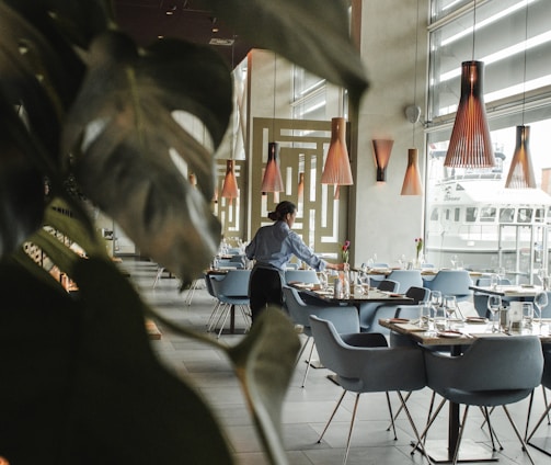 woman in front on brown dining table and chairs inside building