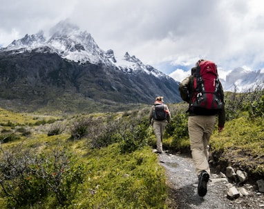 two person walking towards mountain covered with snow