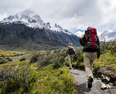 two person walking towards mountain covered with snow