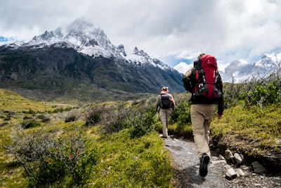 Dos personas caminando hacia una montaña cubierta de nieve