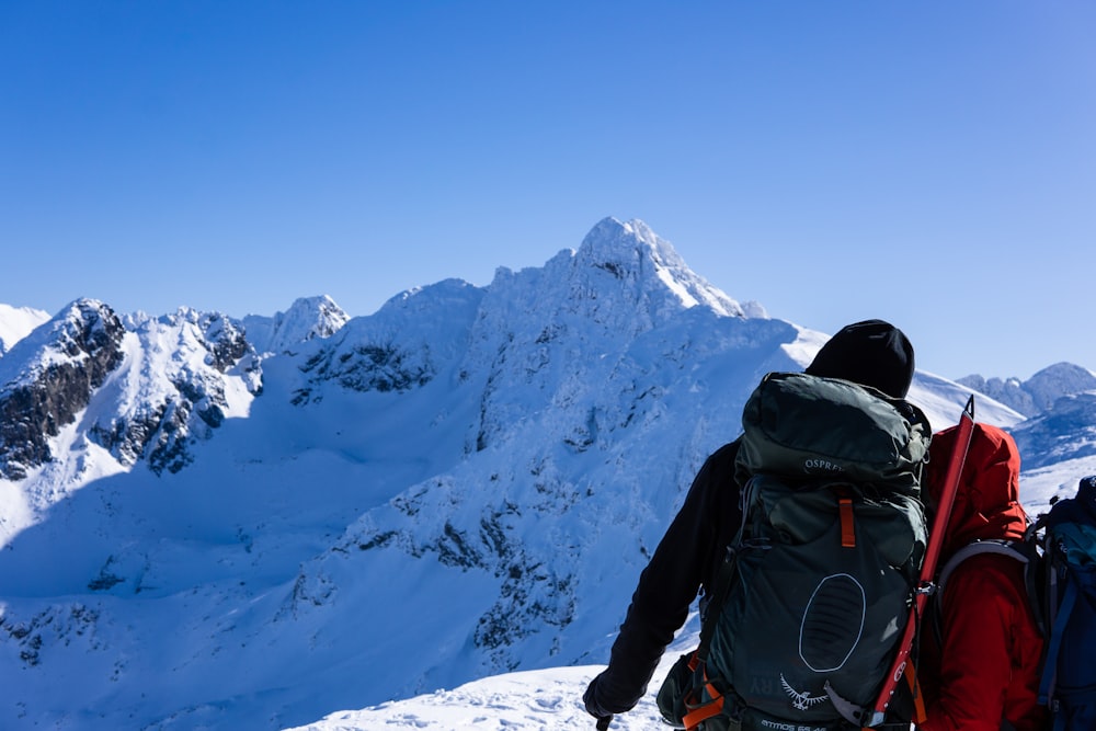 person sitting on snow covered mountain under blue sky