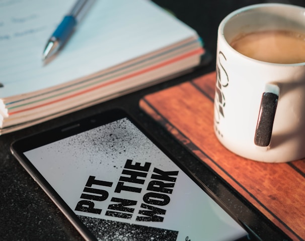 Honor smartphone beside mug and paper with pen