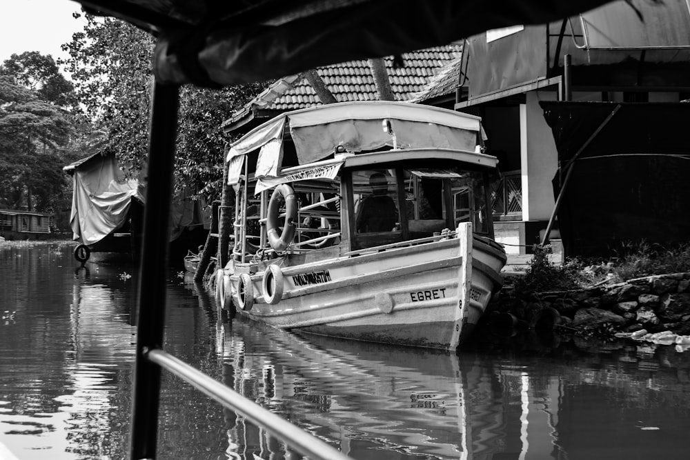 white tug boat docked beside concrete structure