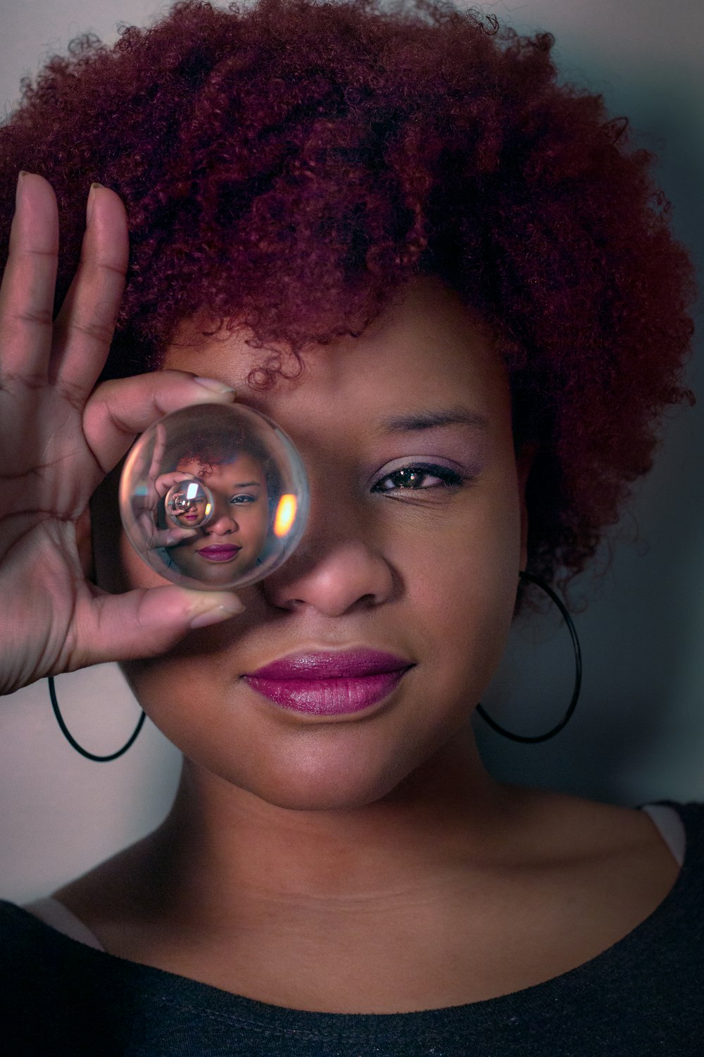 mujer sosteniendo cubriendo el ojo derecho con bola de vidrio transparente